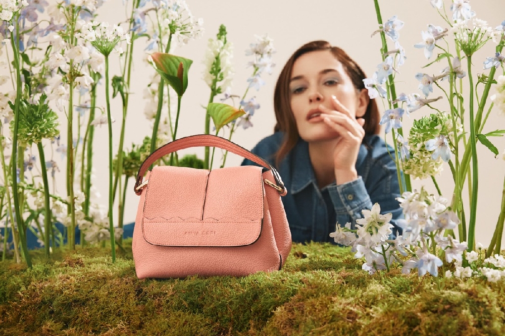 femeie care se uită la o geantă așezată pe iarbă 