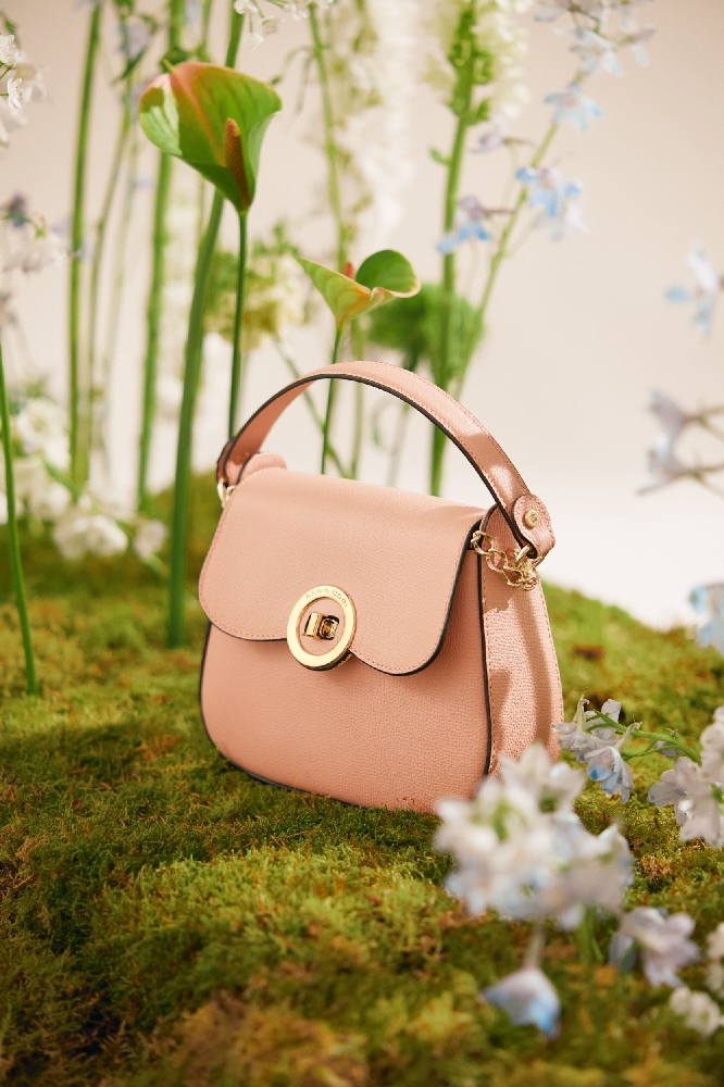 poșetă roz pudră așezată pe iarbă 